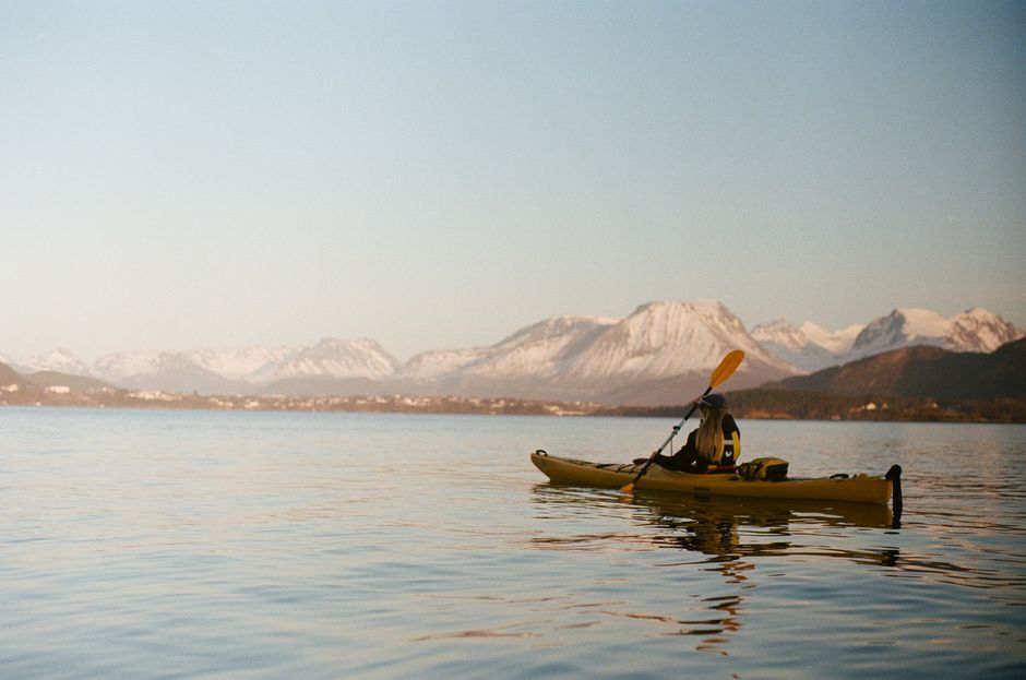 A solo kayaker enjoys peaceful waters with stunning snowy mountains in Ålesund, Norway.